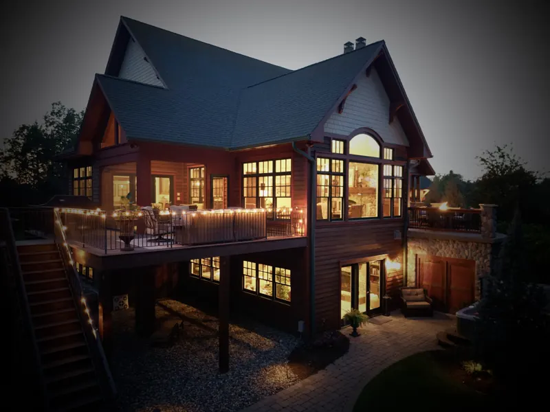 Lake home at dusk with lit decks and stone patio